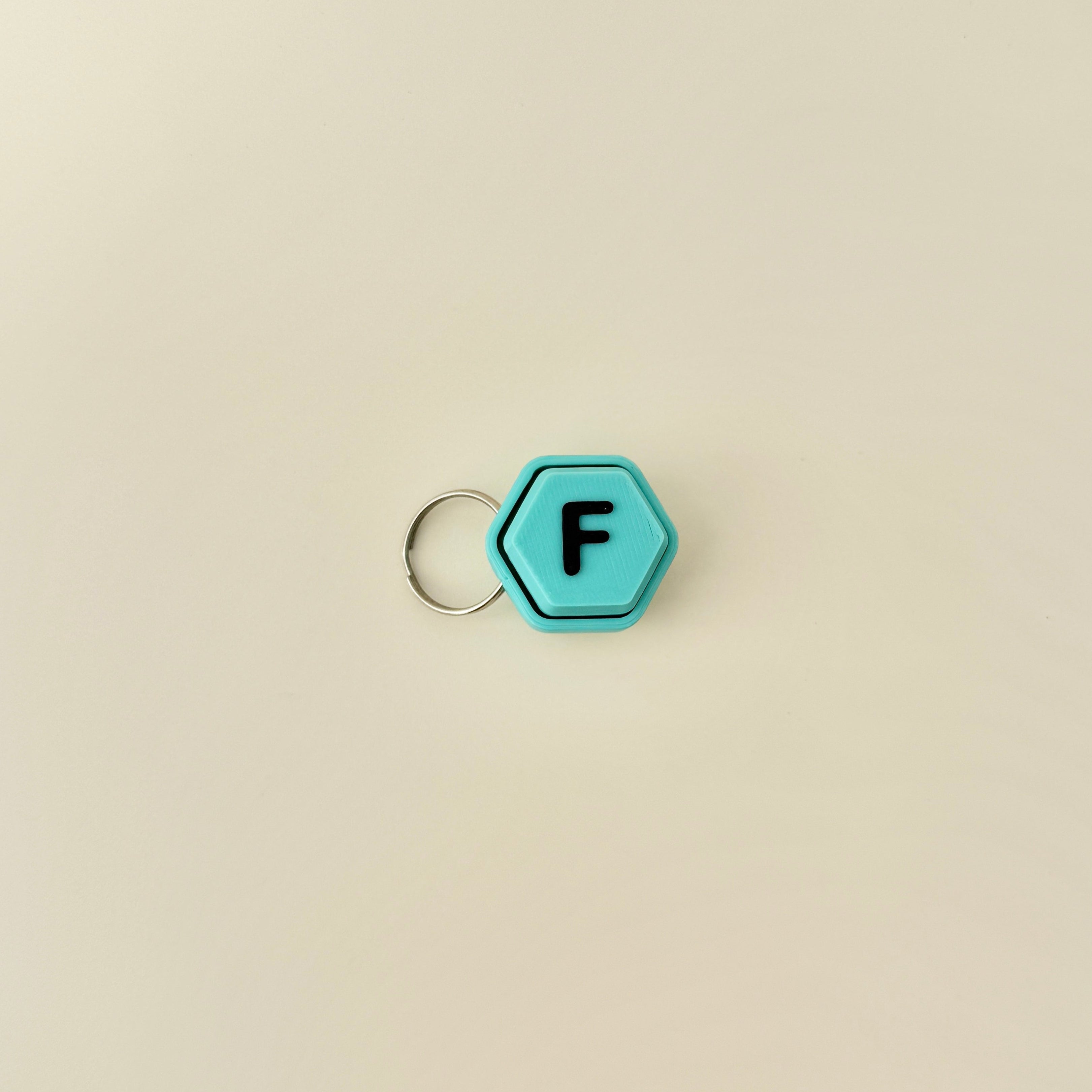 A compact hexagonal fidget toy that clicks when pressed, available with all 26 letters of the alphabet.