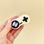 Small handheld clicker with two satisfying buttons in a nostalgic gamepad style.
