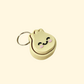A beige dumpling-shaped fidget toy with black eyes, pink cheeks, and a smile, attached to a keychain for easy portability.