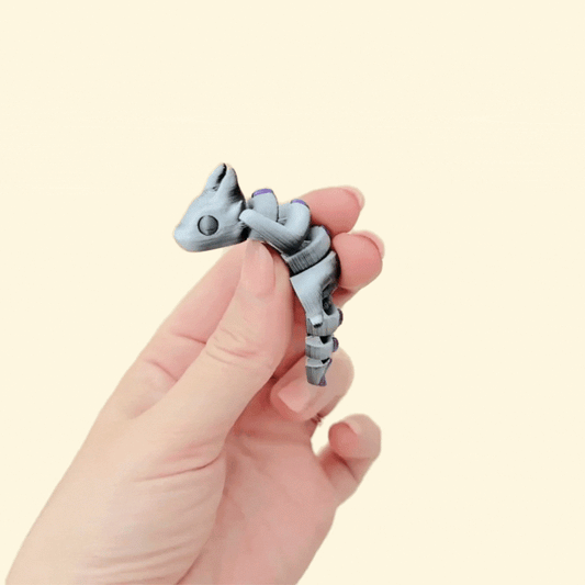 Articulated dragon fidget toy in a colour-shifting black, white, and silver finish with purple detail and black eyes