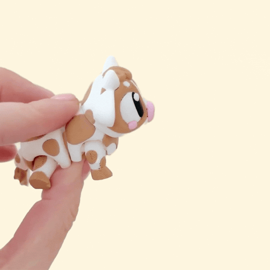 A cute baby cow fidget toy featuring a movable body, legs, and tail for sensory play.