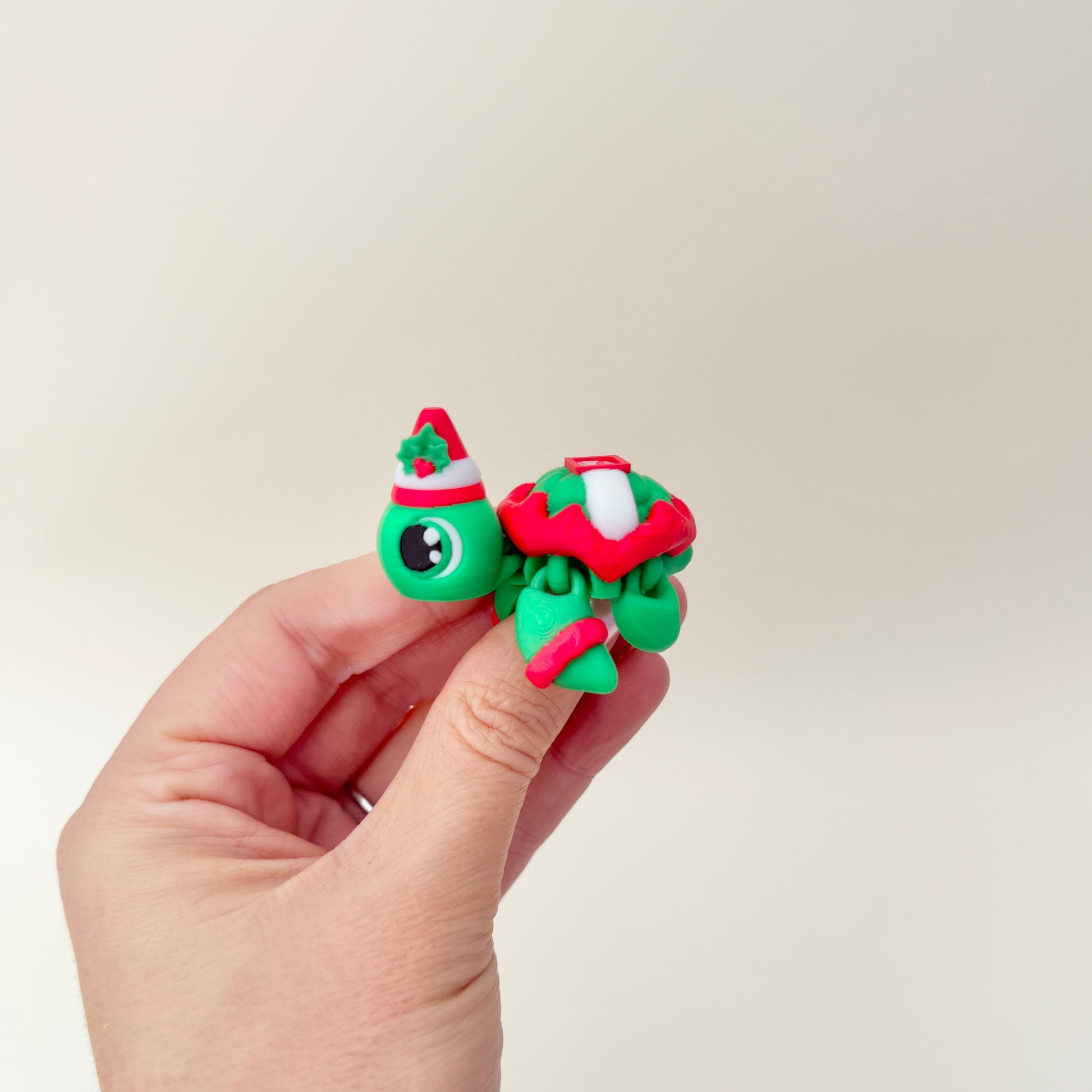 Mini elf turtle with raised shell details and smooth joints for gentle wiggles, bright festive colours, calming tactile fidget for everyday use.
