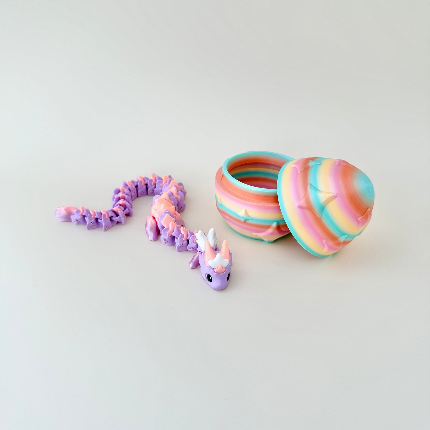 Fully articulated dragon in pastel tones with a matching rainbow egg decorated with embossed star details.