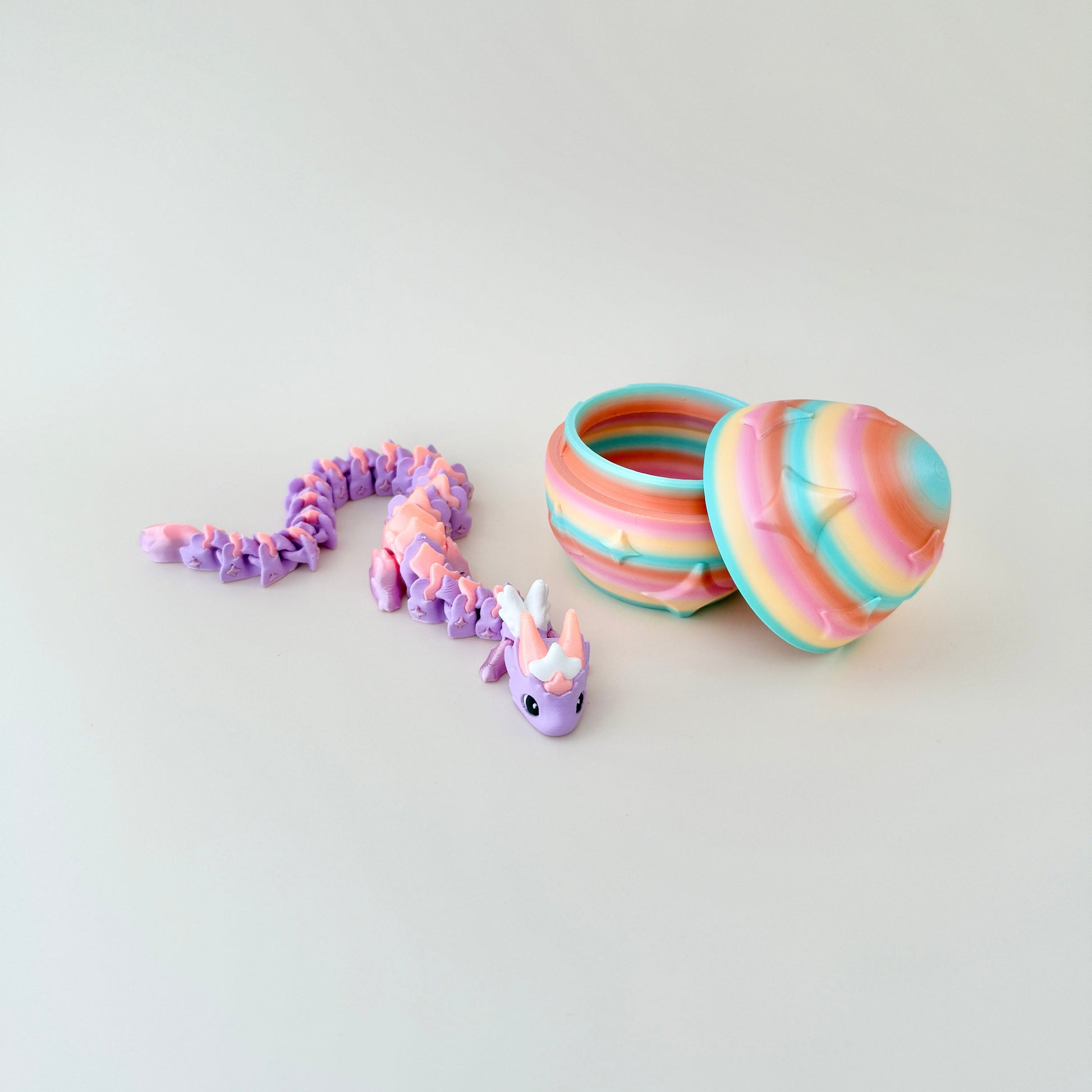 Fully articulated dragon in pastel tones with a matching rainbow egg decorated with embossed star details.
