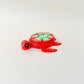 A vibrant red turtle fidget toy with white seed details and a green leaf design for sensory play.
