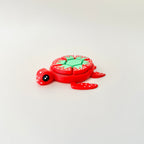 A vibrant red turtle fidget toy with white seed details and a green leaf design for sensory play.