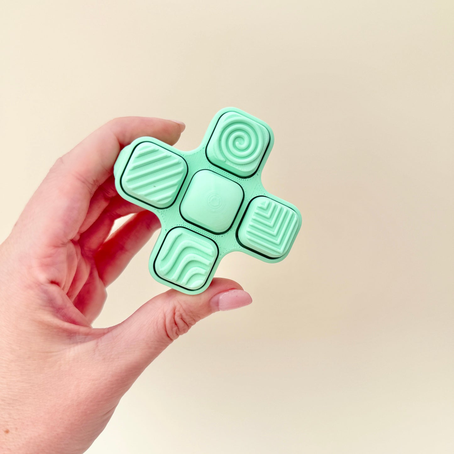 Portable clicker fidget with multiple textured sections and wrist strap attachment.