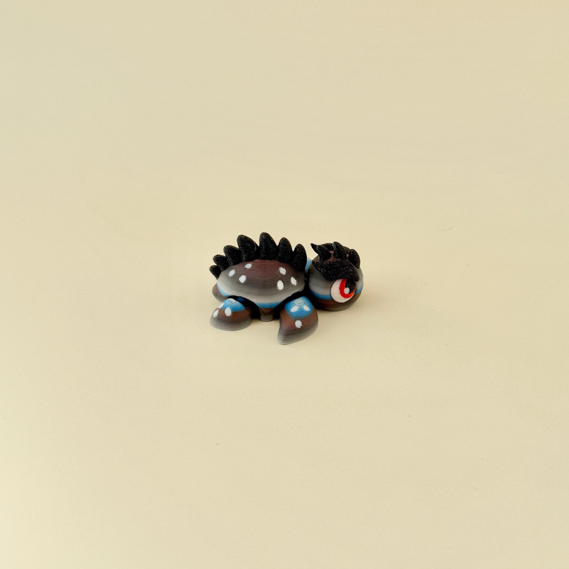Small dragon-inspired turtle fidget with dramatic red eyes and movable limbs for focus and stress relief.