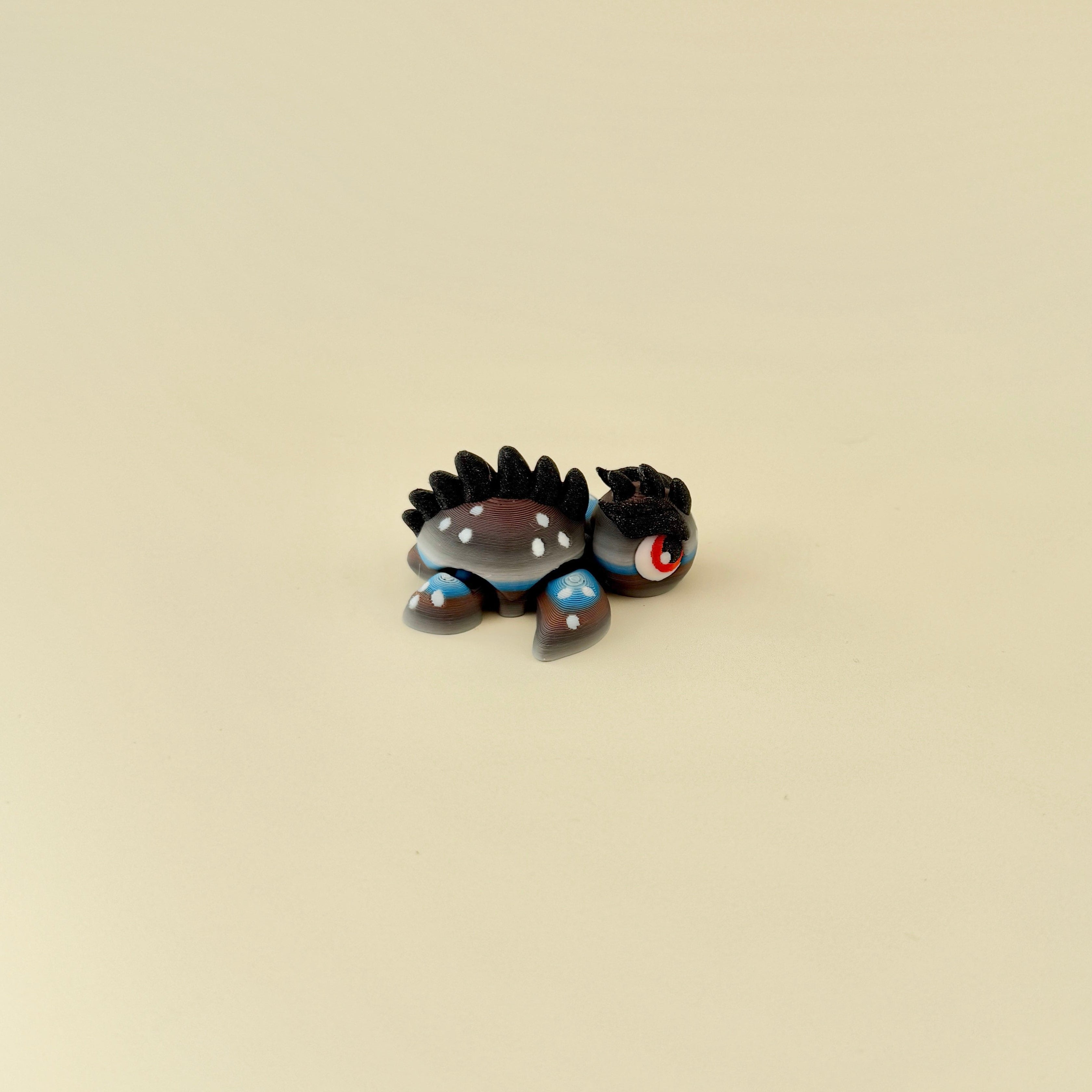 Small dragon-inspired turtle fidget with dramatic red eyes and movable limbs for focus and stress relief.
