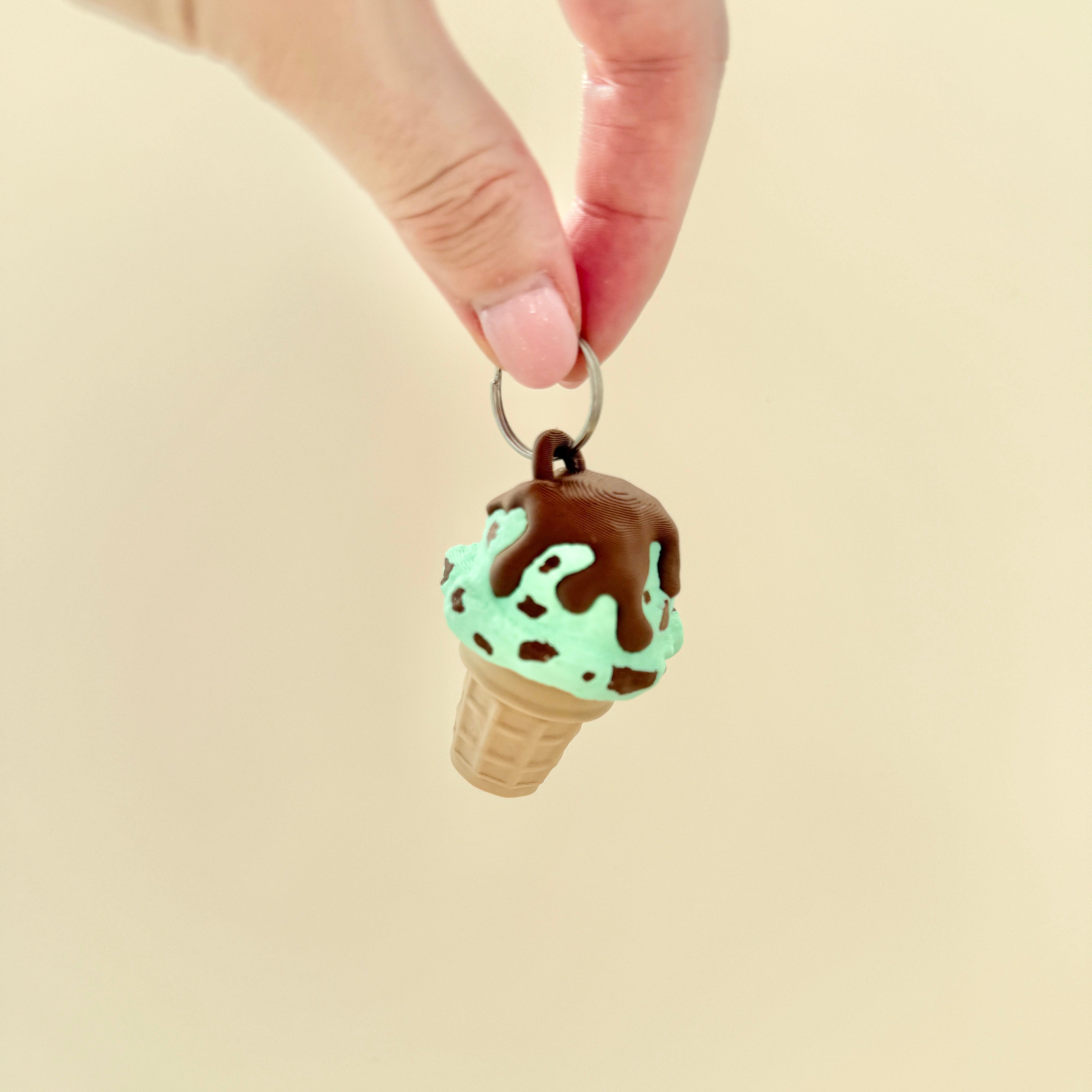 Compact clicker fidget toy in an ice cream shape, finished with sprinkles, sauce, or swirl effects.