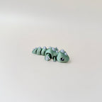 Fully articulated Flexasaurus dinosaur fidget toy in strawberry red with gold spikes and claws.