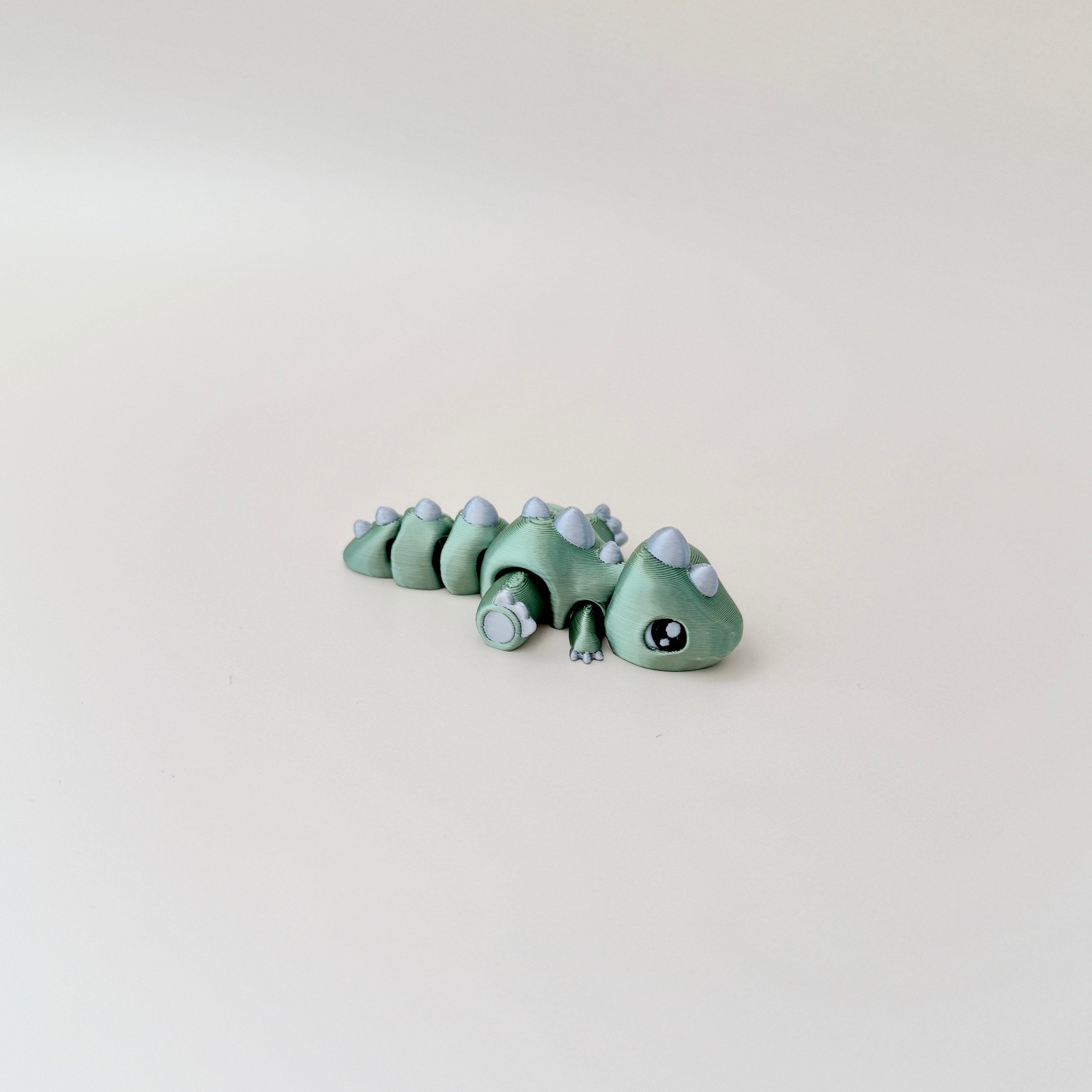 Fully articulated Flexasaurus dinosaur fidget toy in strawberry red with gold spikes and claws.