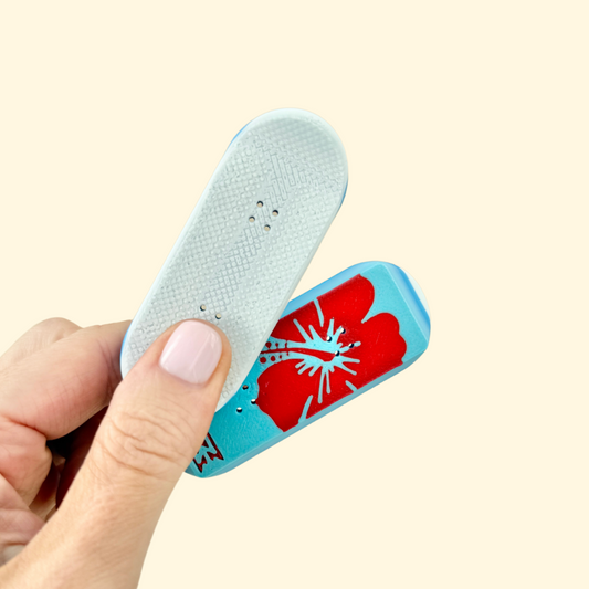A pair of skateboard-shaped magnetic fidget toys with red hibiscus flowers and blue gradient detailing.