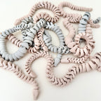 A flexible, articulated snake-shaped fidget toy available in colour-changing, nude, and grey matte options.