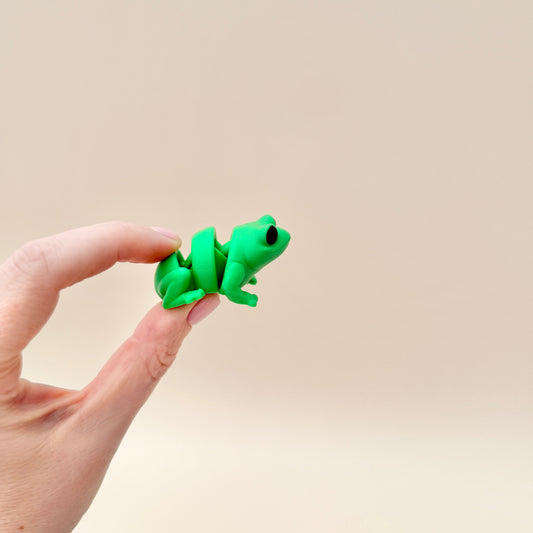 Small green frog fidget toy with movable legs and body, ideal for stress relief and focus.