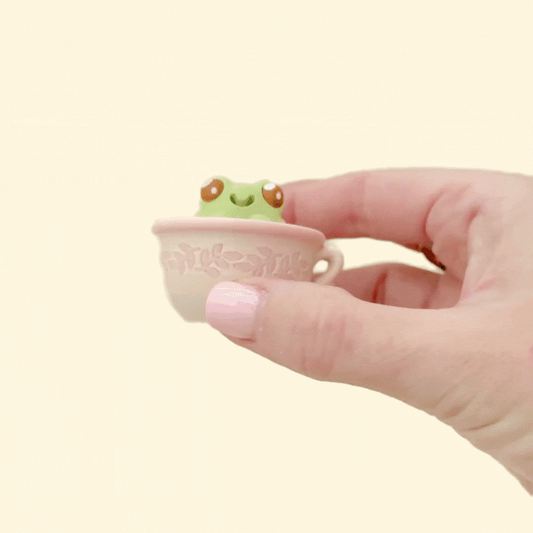 Small frog figure in a cup designed for press-and-release clicking.
