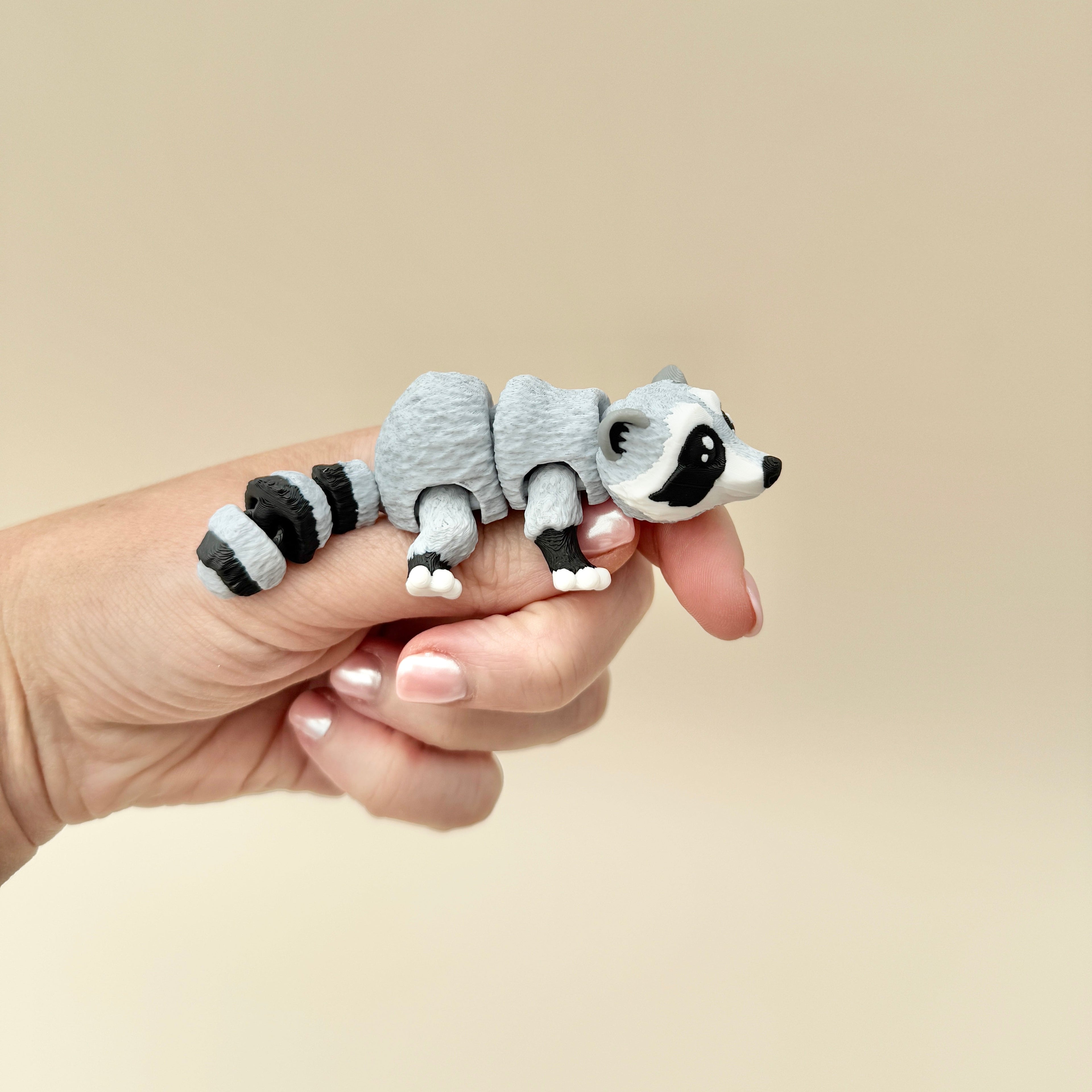 Fidget toy shaped like a raccoon, featuring movable legs, tail, and head for sensory play.