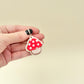 Red-and-white mushroom-shaped sensory toy on loop for bags or keys.
