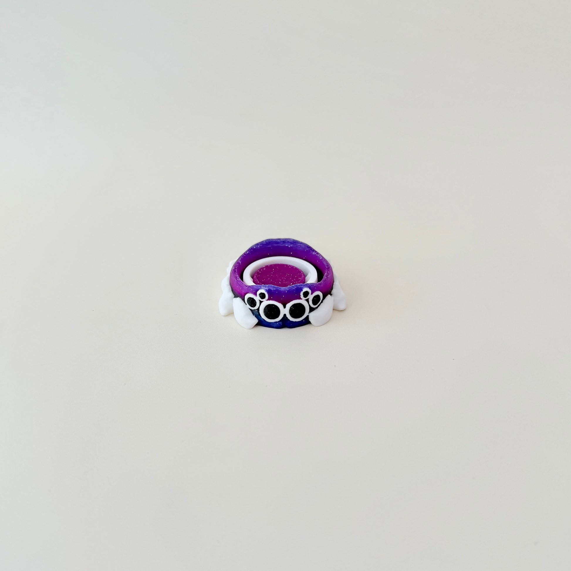Compact spinner with spider grip and galaxy-glitter ring; smooth spin for tactile focus.
