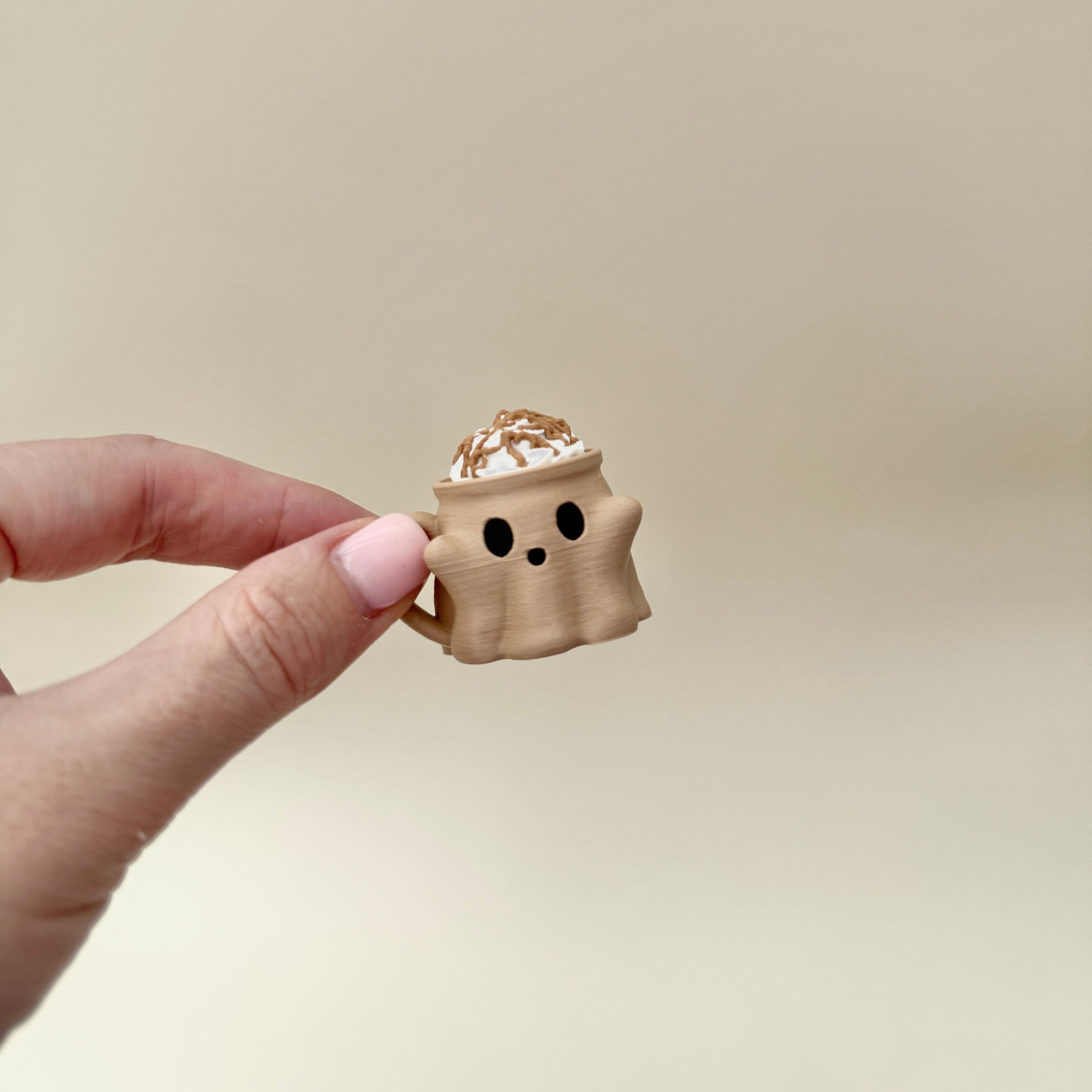 Nude ghost-face cup with textured cream swirl designed for handheld clicking.
