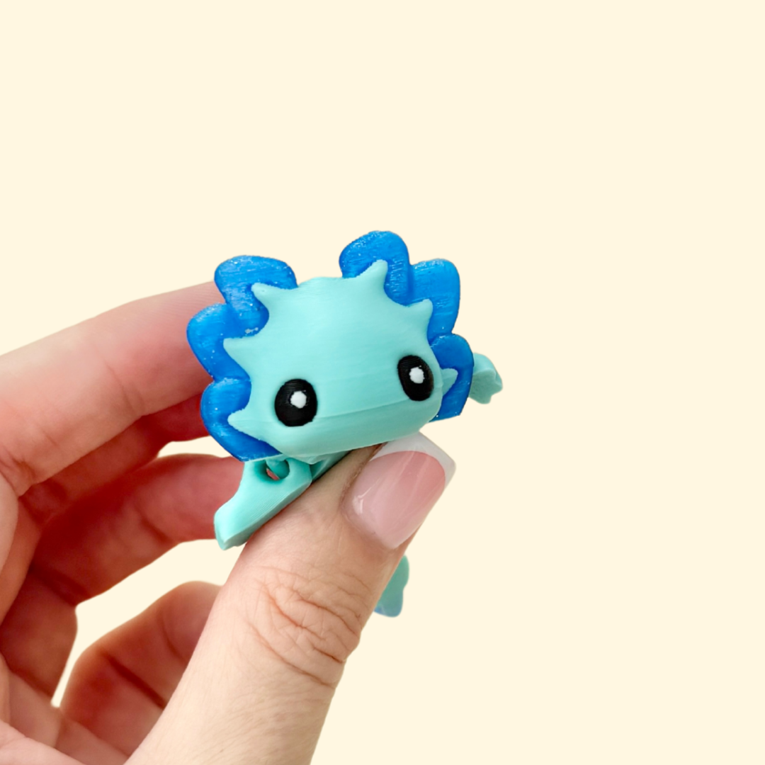 Flexible dragon-shaped stim toy with fins and glittery blue detailing for tactile and visual stimming.