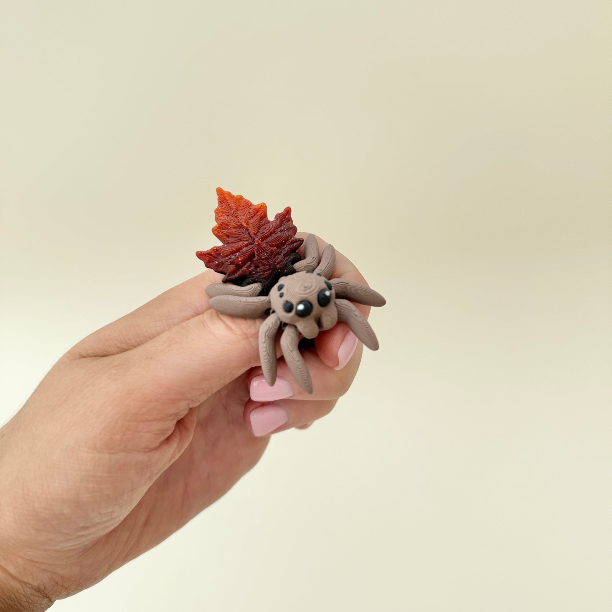 Spider fidget featuring a brown-to-amber glitter leaf back designed for silent sensory use.
