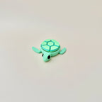 Turtle clicker toy in shades of green and blue, with 7 clickers and a flexible body for tactile play.