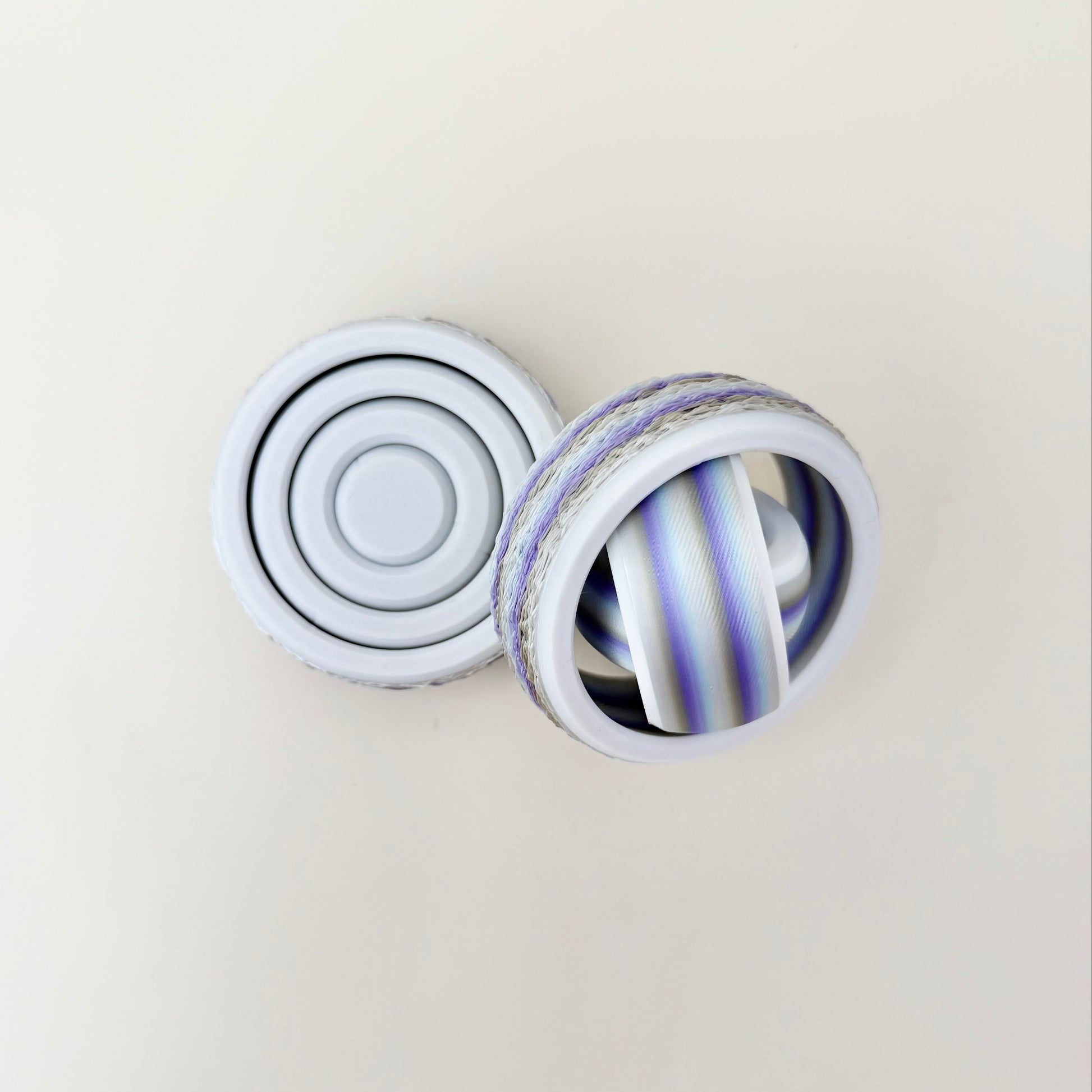 Gyro-style four-ring fidget spinner with fuzzy outer edge for grippy, tactile thumb rolls.
