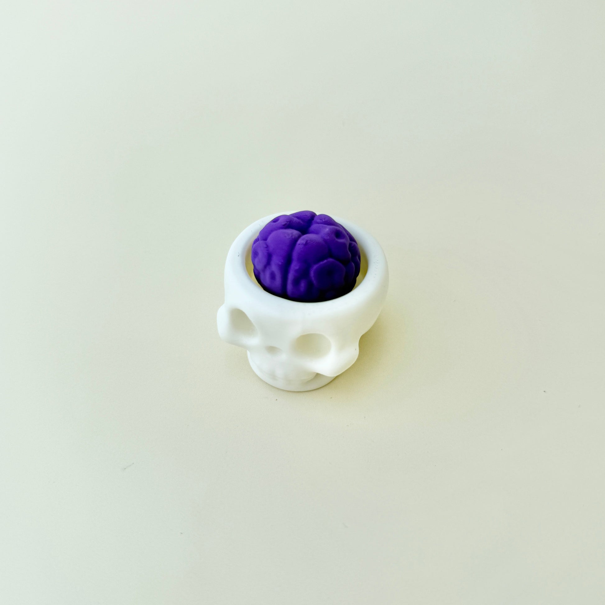 Compact skull fidget with a brain-shaped button for stress relief
