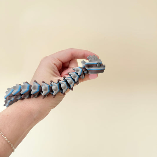 Long articulated snake in dark grey and blue tones with bumpy scales
