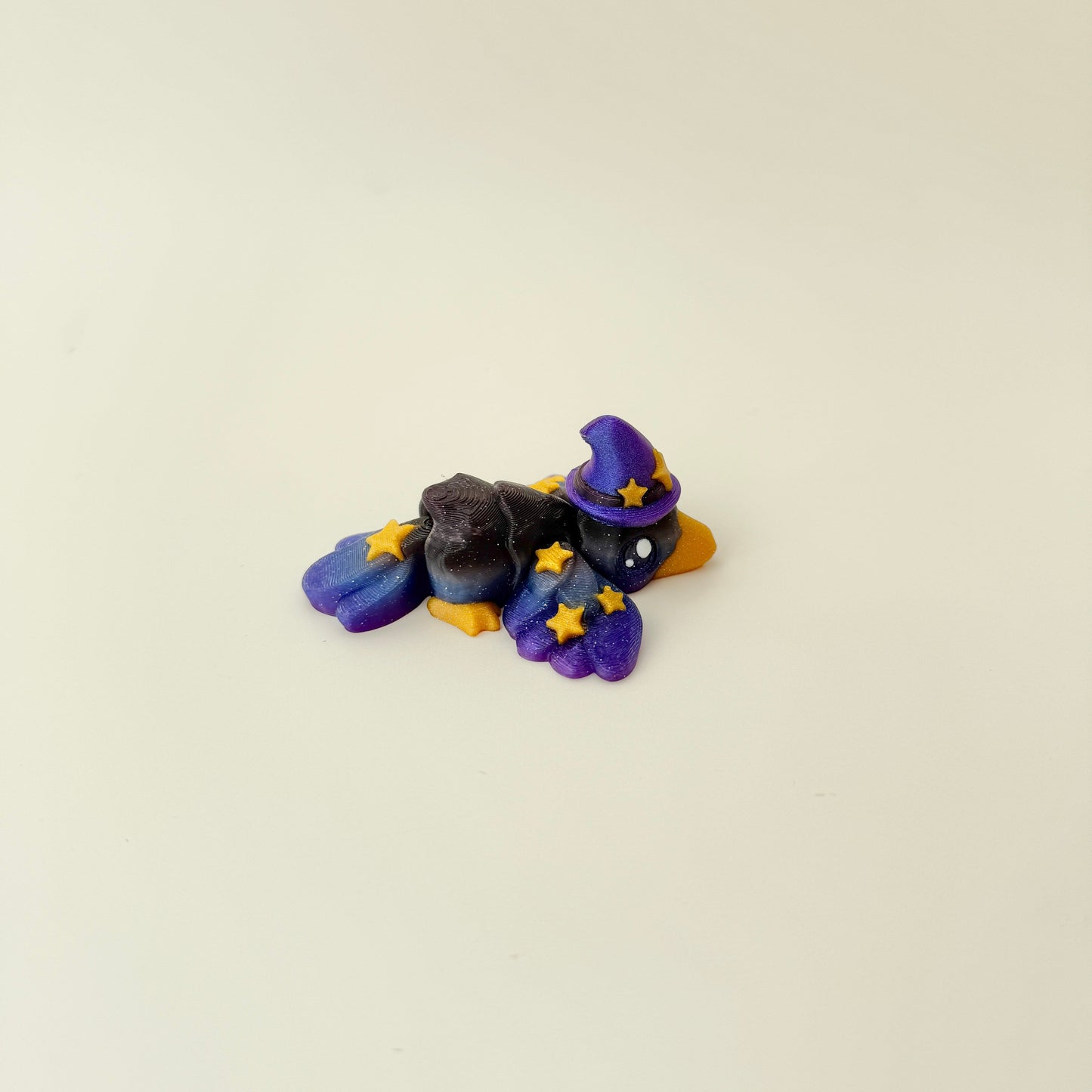 Cute seasonal crow charm with glitter sheen and an iridescent purple hat.