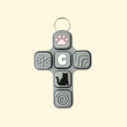 Cross-shaped fidget toy with various textured and shaped buttons on a beige background