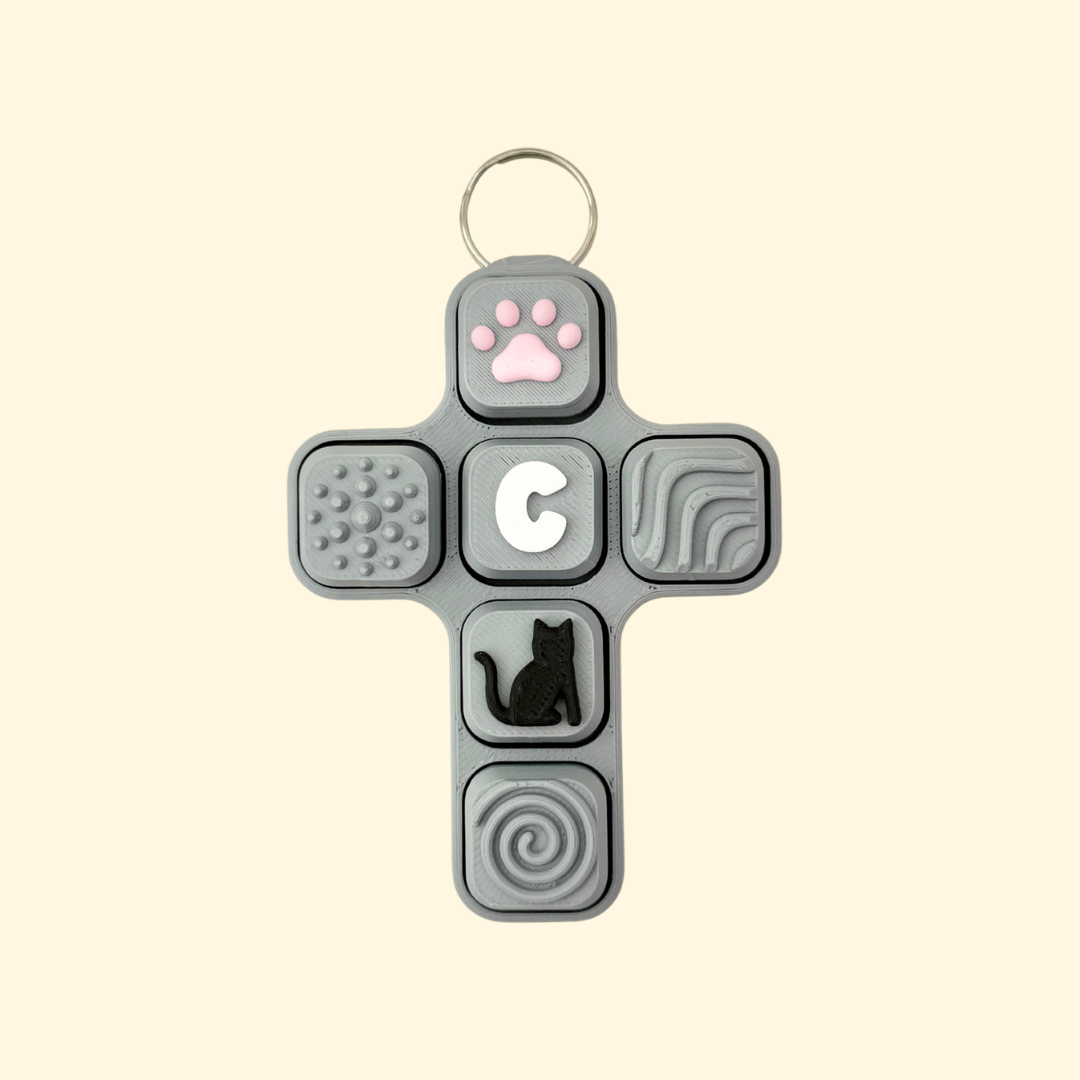Cross-shaped fidget toy with various textured and shaped buttons on a beige background