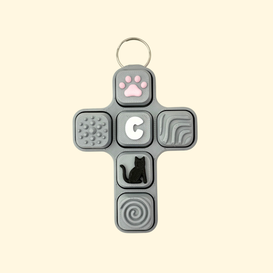 Cross-shaped fidget toy with various textured and shaped buttons on a beige background