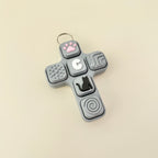 Gray cross-shaped fidget toy with various textured buttons on a beige background