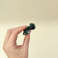 Cute 5 cm turtle ornament-style fidget with leafy ridges, black eyes, and a red ribbon bow detail.
