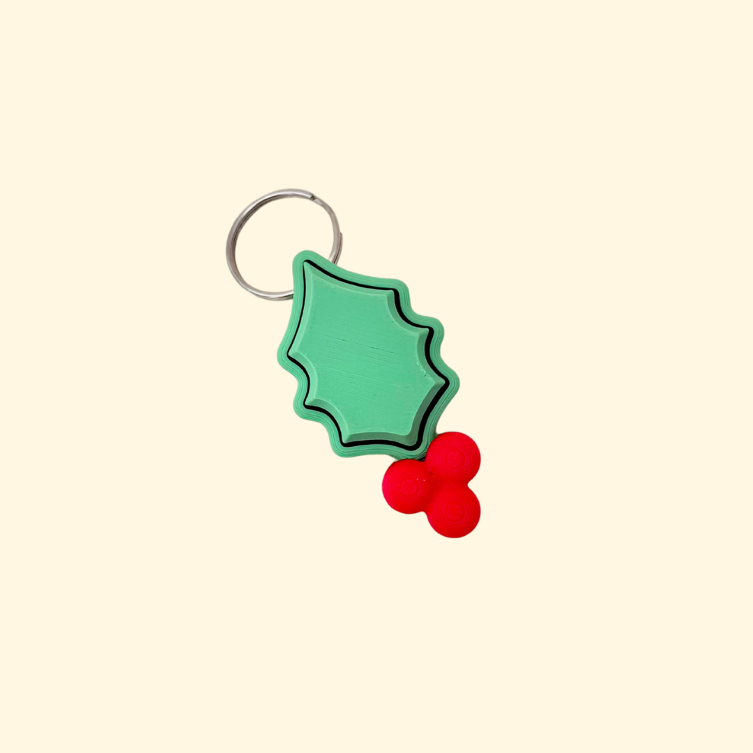 Simple holly-shaped fidget keyring with smooth edges and click centre, 5 cm, festive colours.
