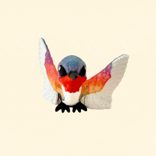 A rainbow-coloured hummingbird fidget toy with articulated wings and a sleek black beak.