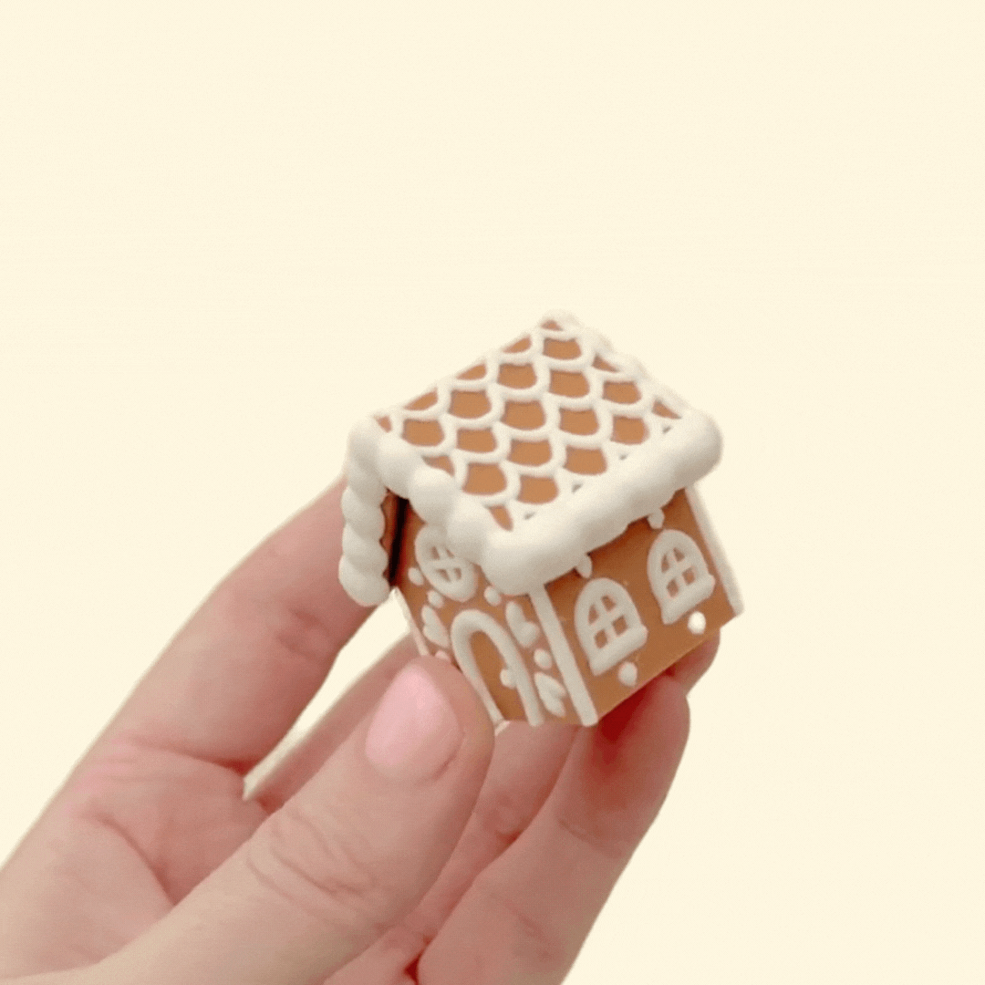 Small gingerbread cottage clicker; press-down roof gives tactile click, textured icing details, smooth body for tracing.
