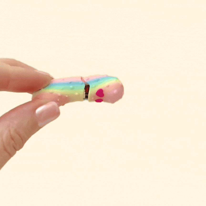 A shiny, colour-changing rainbow pickle fidget toy with heart eyes, showing its interactive opening mouth.
