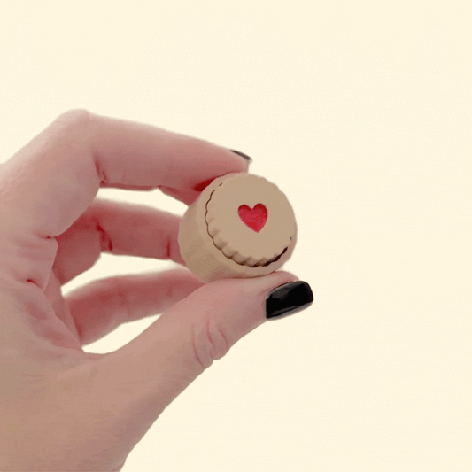 Biscuit style fidget with raised rim and translucent red centre, compact 3 cm size, press action click, optional quiet click upgrade.