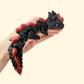Articulated dragon fidget toy with dark colouring and glittery red accents