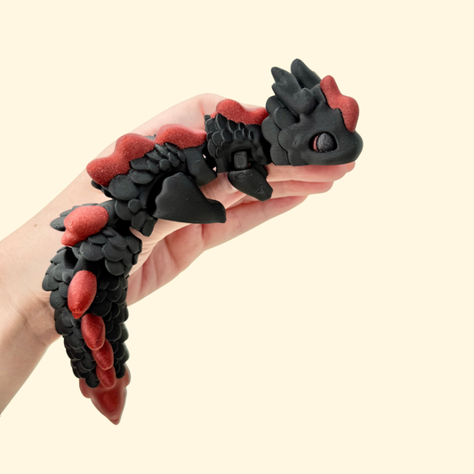 Articulated dragon fidget toy with dark colouring and glittery red accents