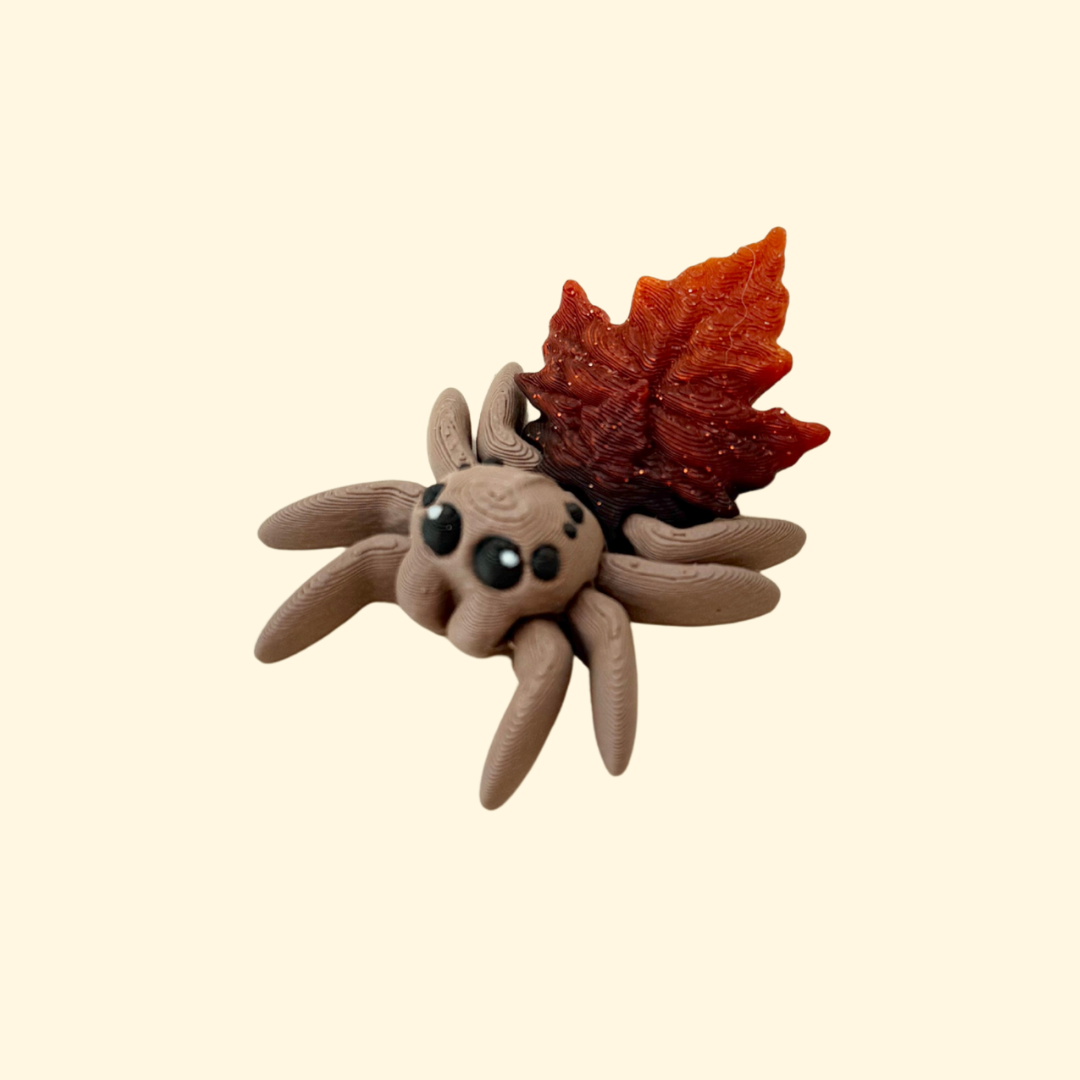 Small articulated spider sensory toy with glitter leaf back and moving legs, silent and pocket sized.
