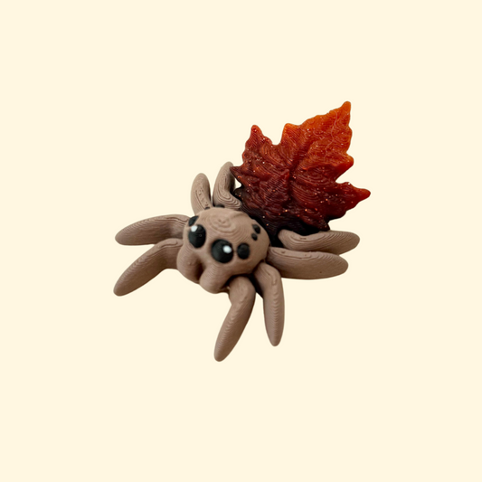 Small articulated spider sensory toy with glitter leaf back and moving legs, silent and pocket sized.
