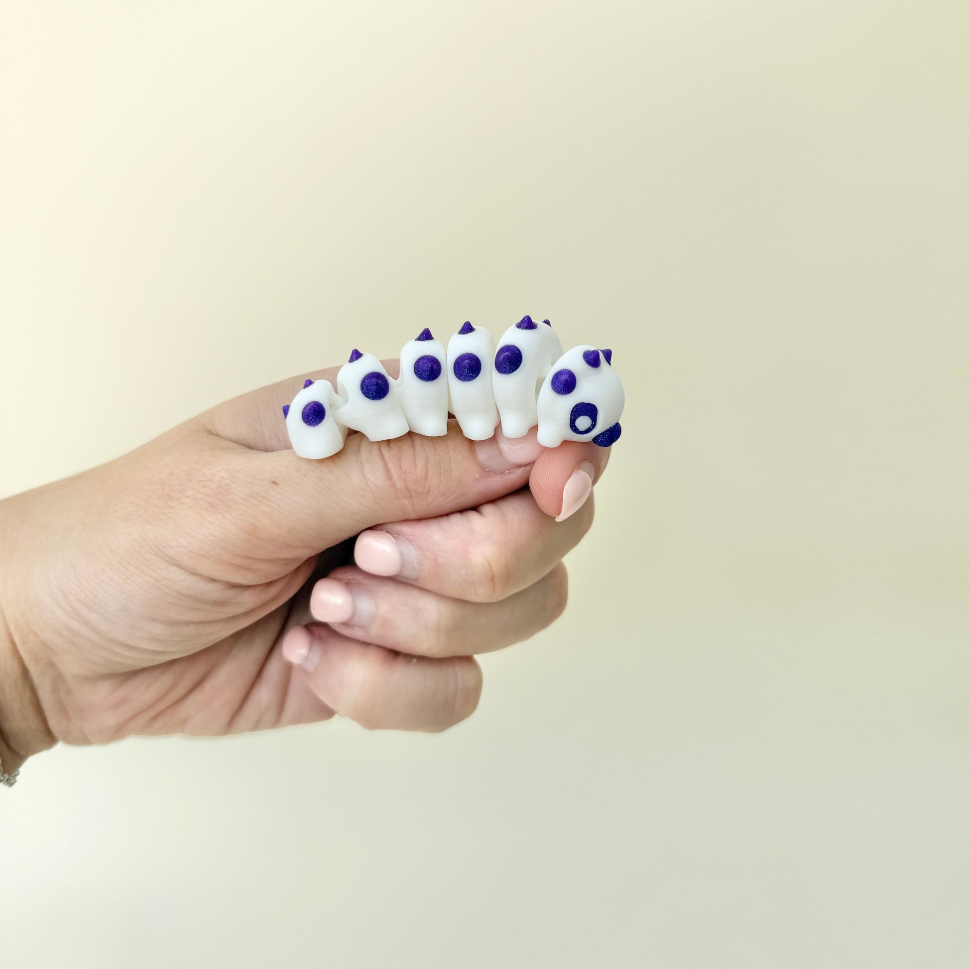 Articulated caterpillar fidget with leaf base for sensory play.
