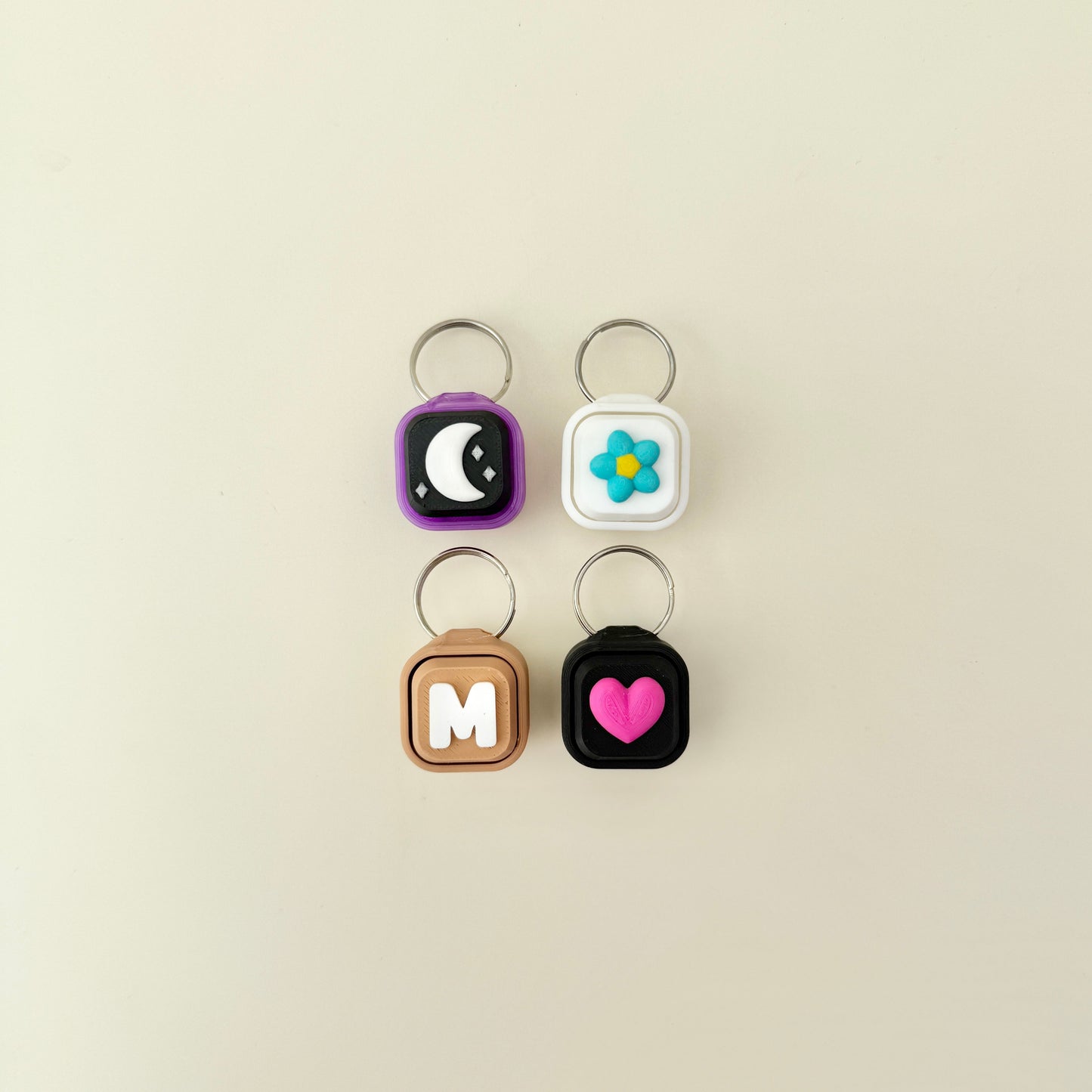 Four keychains with different designs on a beige background