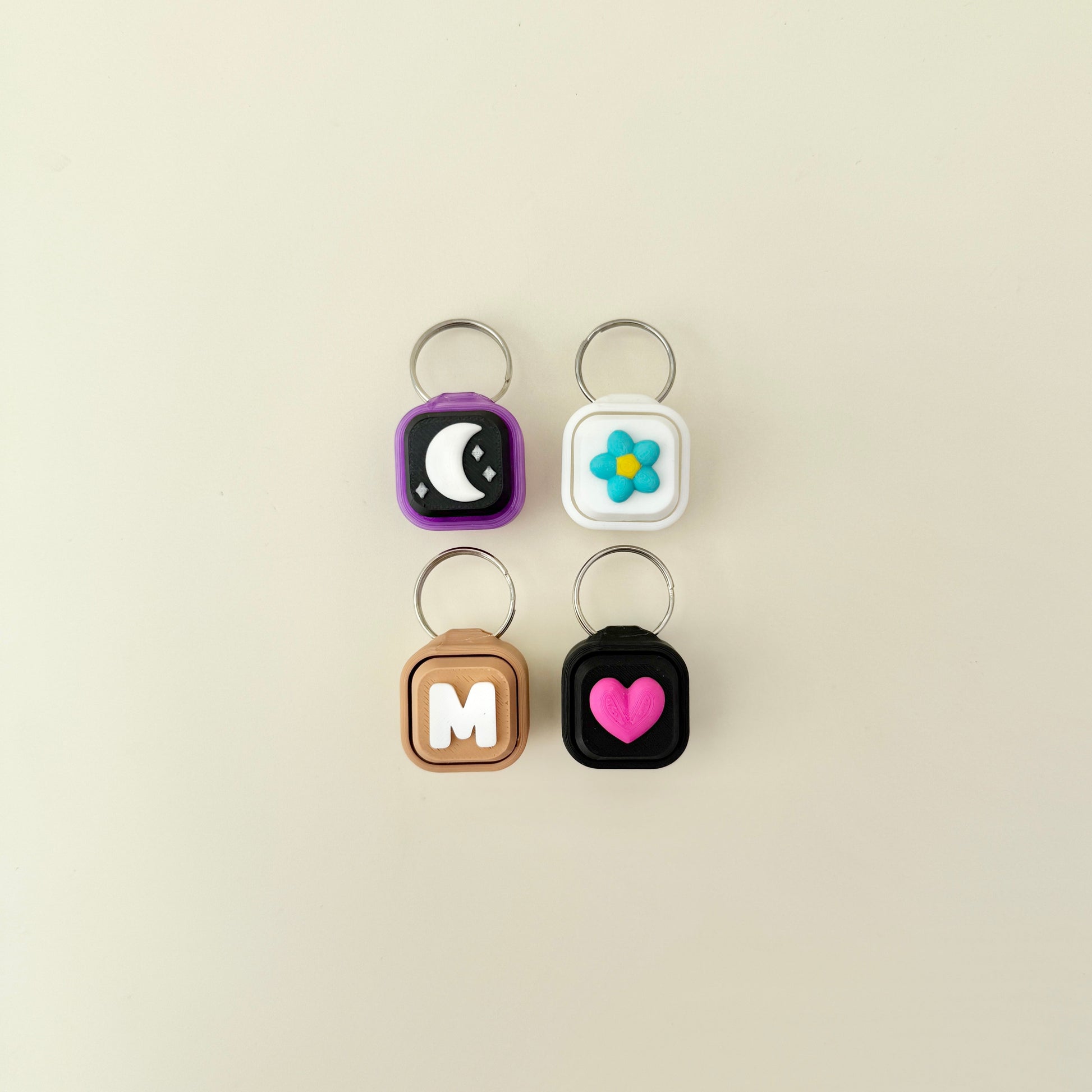 Four keychains with different designs on a beige background