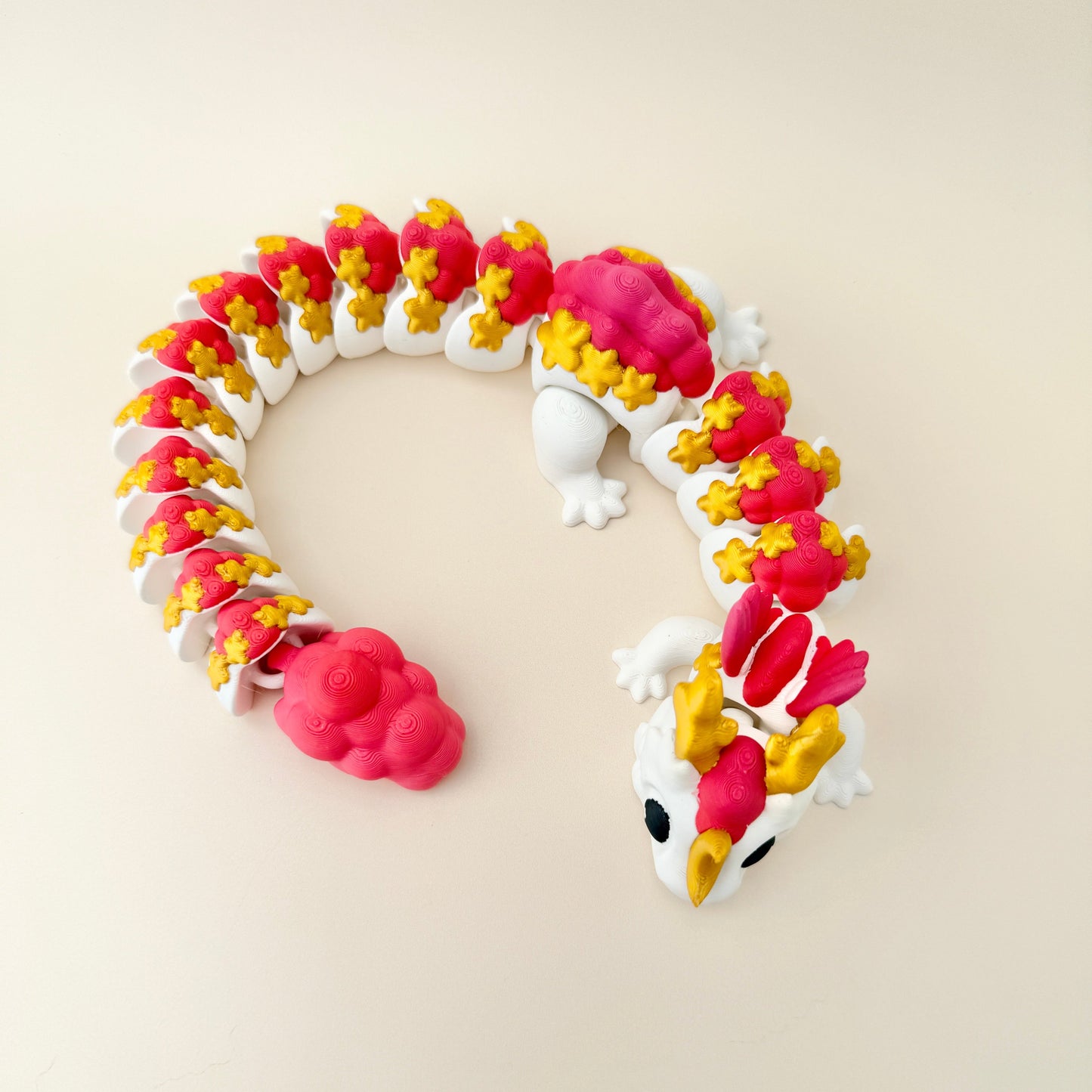 Large fidget dragon toy in white with gold, fiery red, and pink features, perfect for sensory play.