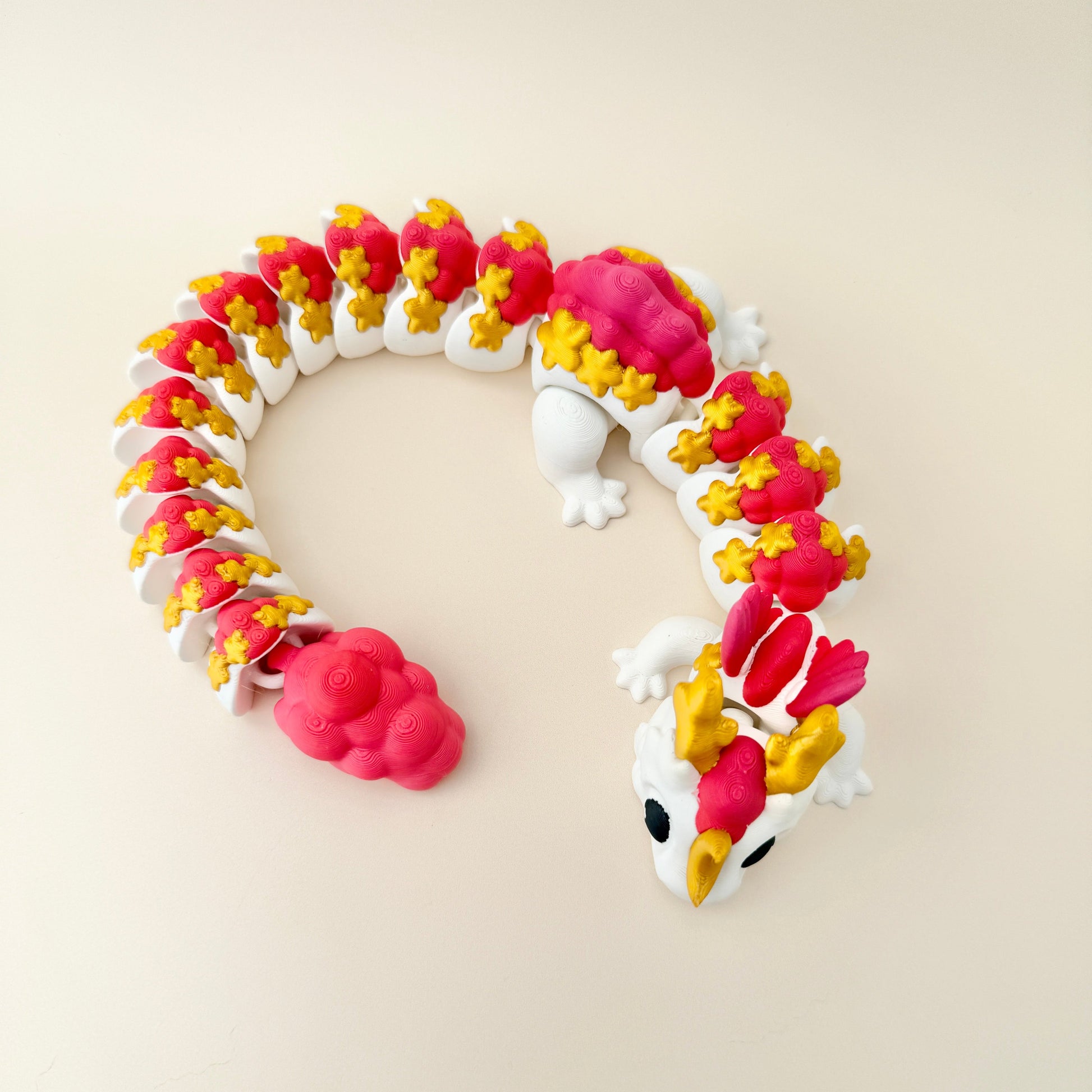 Large fidget dragon toy in white with gold, fiery red, and pink features, perfect for sensory play.